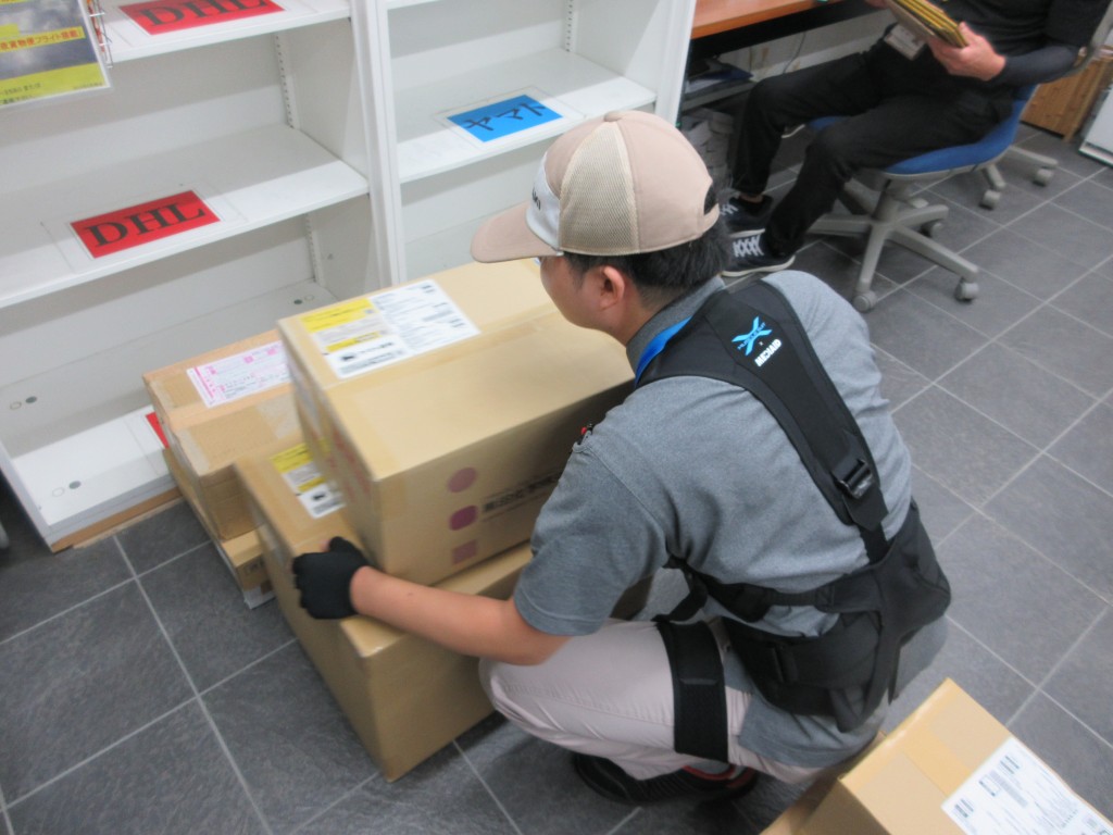矢崎部品ものづくりセンターのメールルームでマッスルスーツ Soft-Light2を着用し荷物を持ち上げる作業者