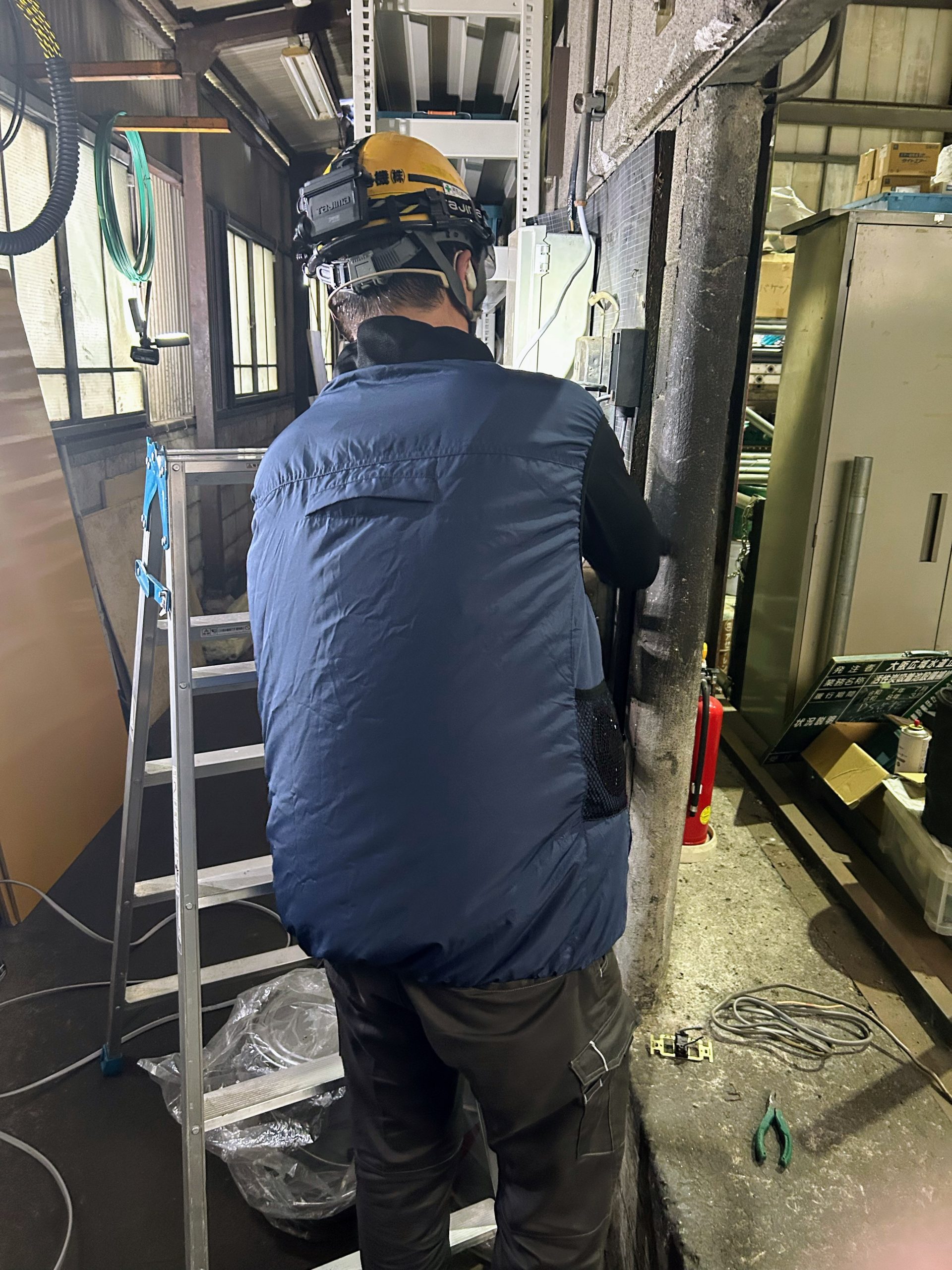 高所作業の現場でマッスルスーツ COOL VEST 2を着用して設備工事を行う様子
