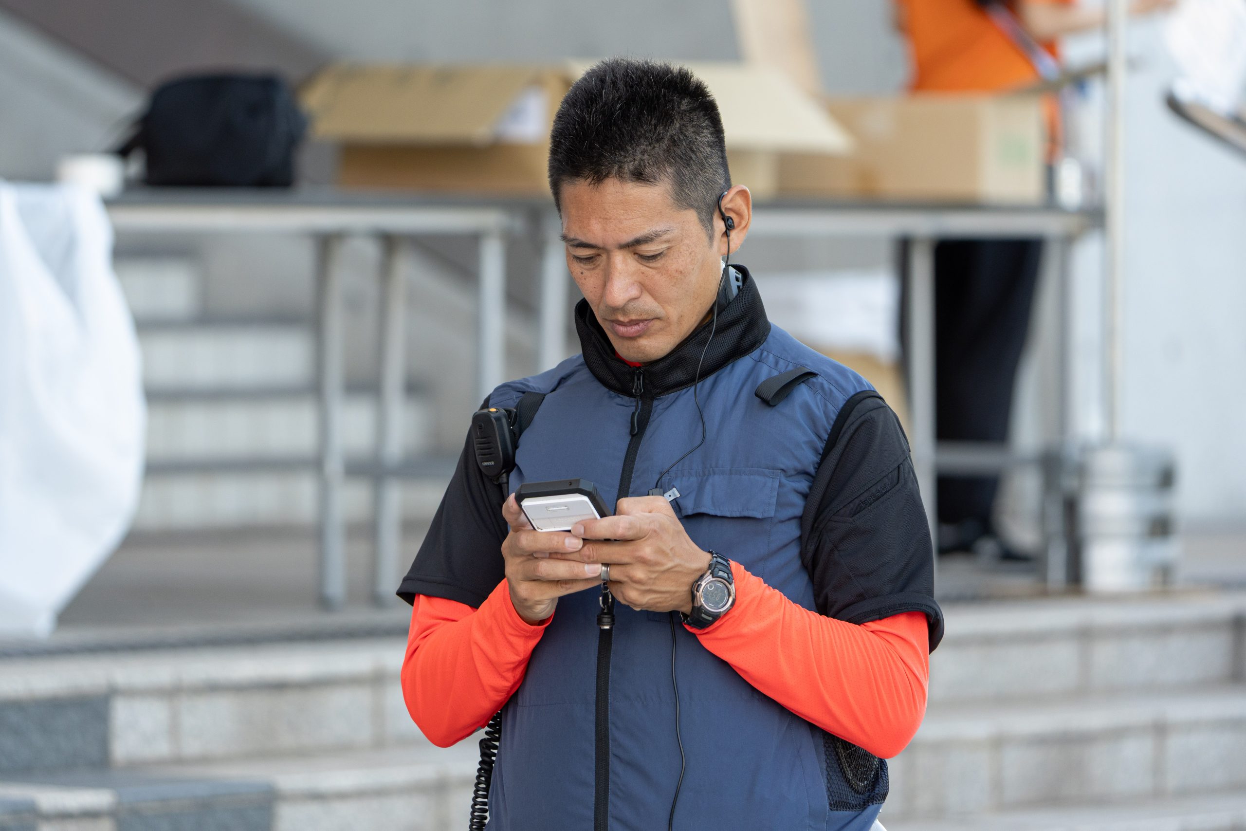マッスルスーツ COOL VEST 2を着用して移動中に端末操作を行うスタッフ