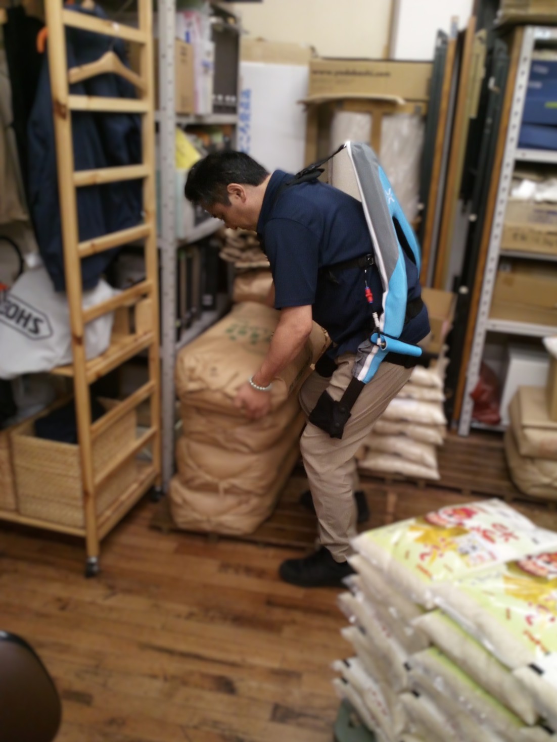 マッスルスーツ Exo-Powerを装着して米袋の積み上げ作業を行う店主の様子